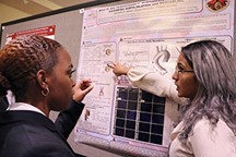 Two students chat in a student poster session.